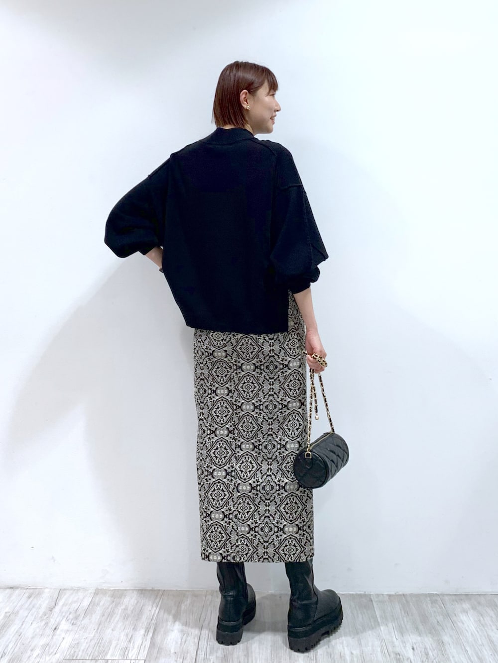 ブラック系のショルダーバッグ、ブラック系のブーツ、ブラック系のスカートを着用したレディースの秋コーディネートの4枚目の写真