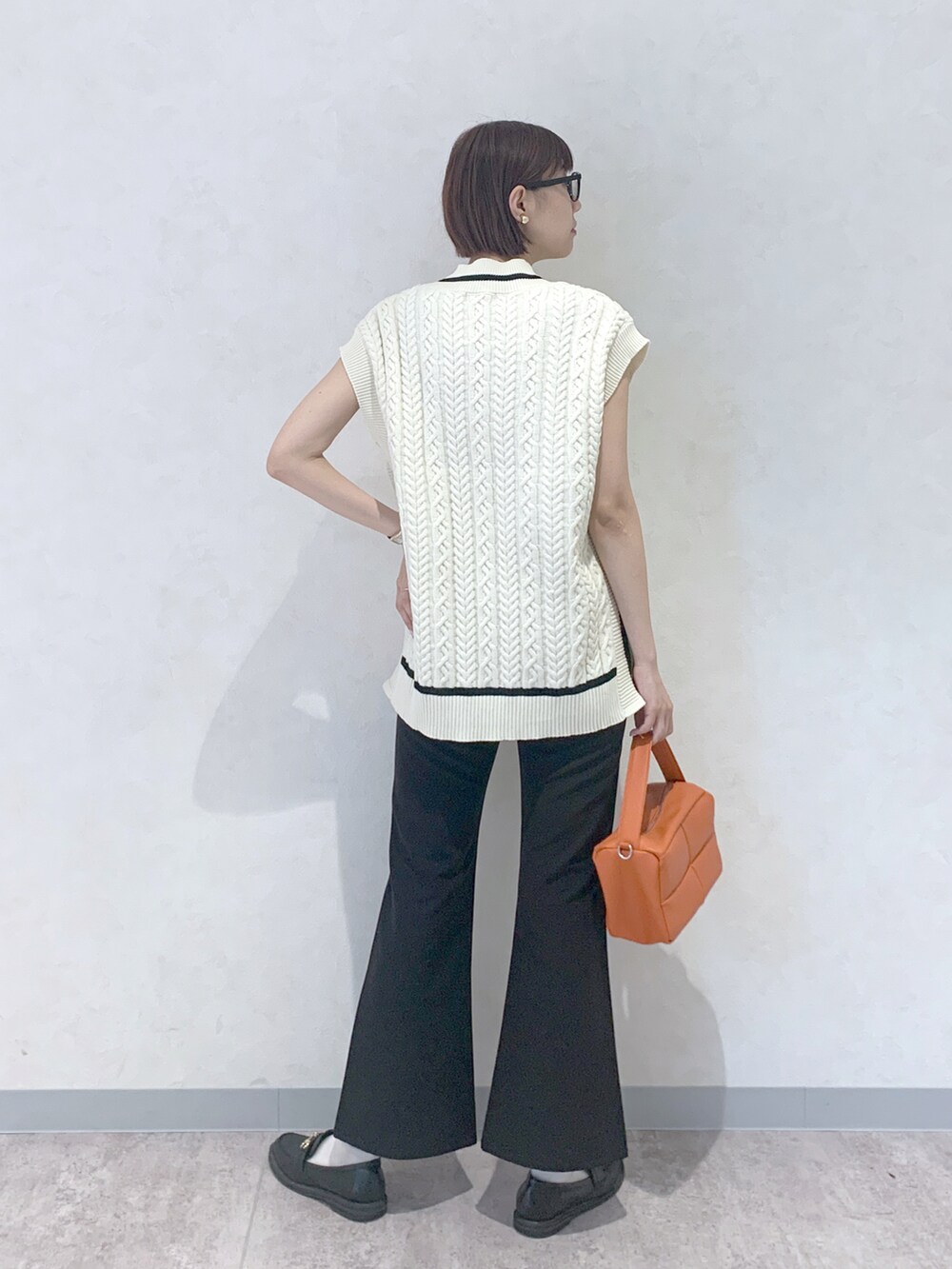 オレンジ系のショルダーバッグ、ブラック系のローファー、ブラック系のスラックスを着用したレディースの夏コーディネートの4枚目の写真