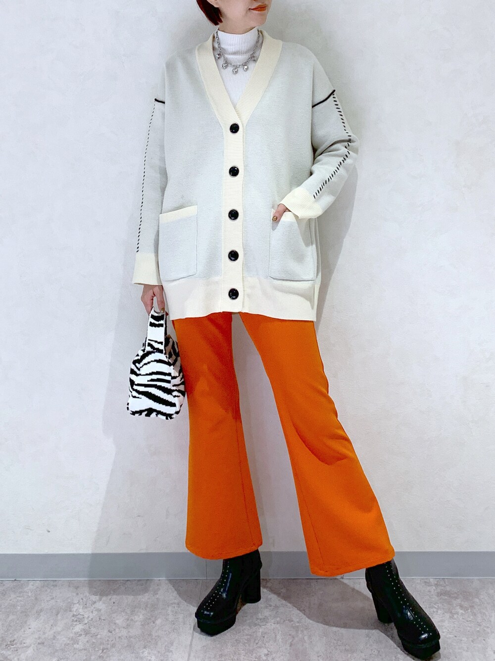 オレンジ系のスラックス、ブラック系のブーツ、その他のバッグを着用したレディースの秋コーディネートの2枚目の写真