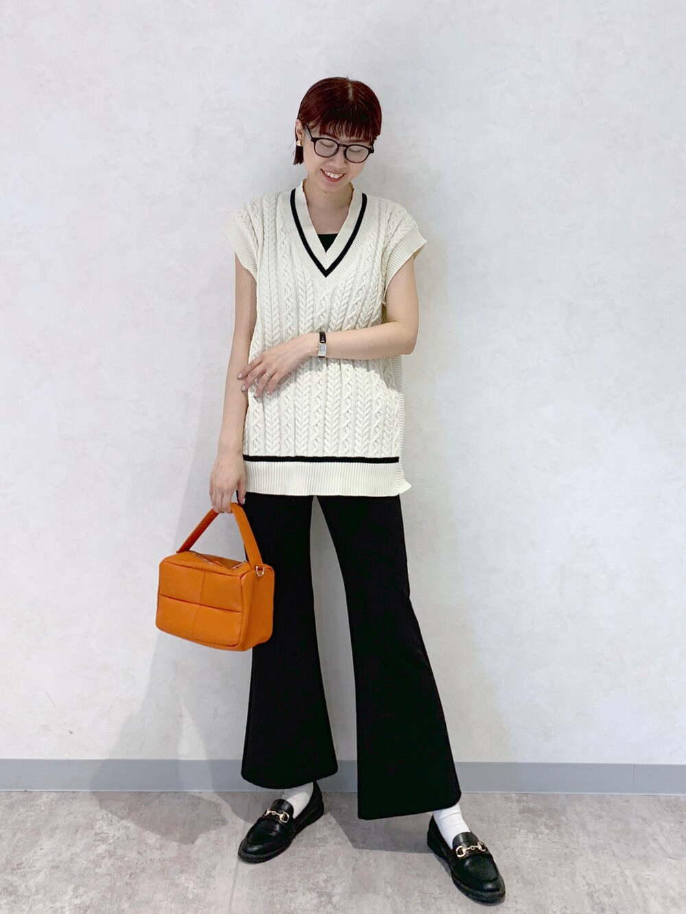 オレンジ系のショルダーバッグ、ブラック系のローファー、ブラック系のスラックスを着用したレディースの夏コーディネートの2枚目の写真