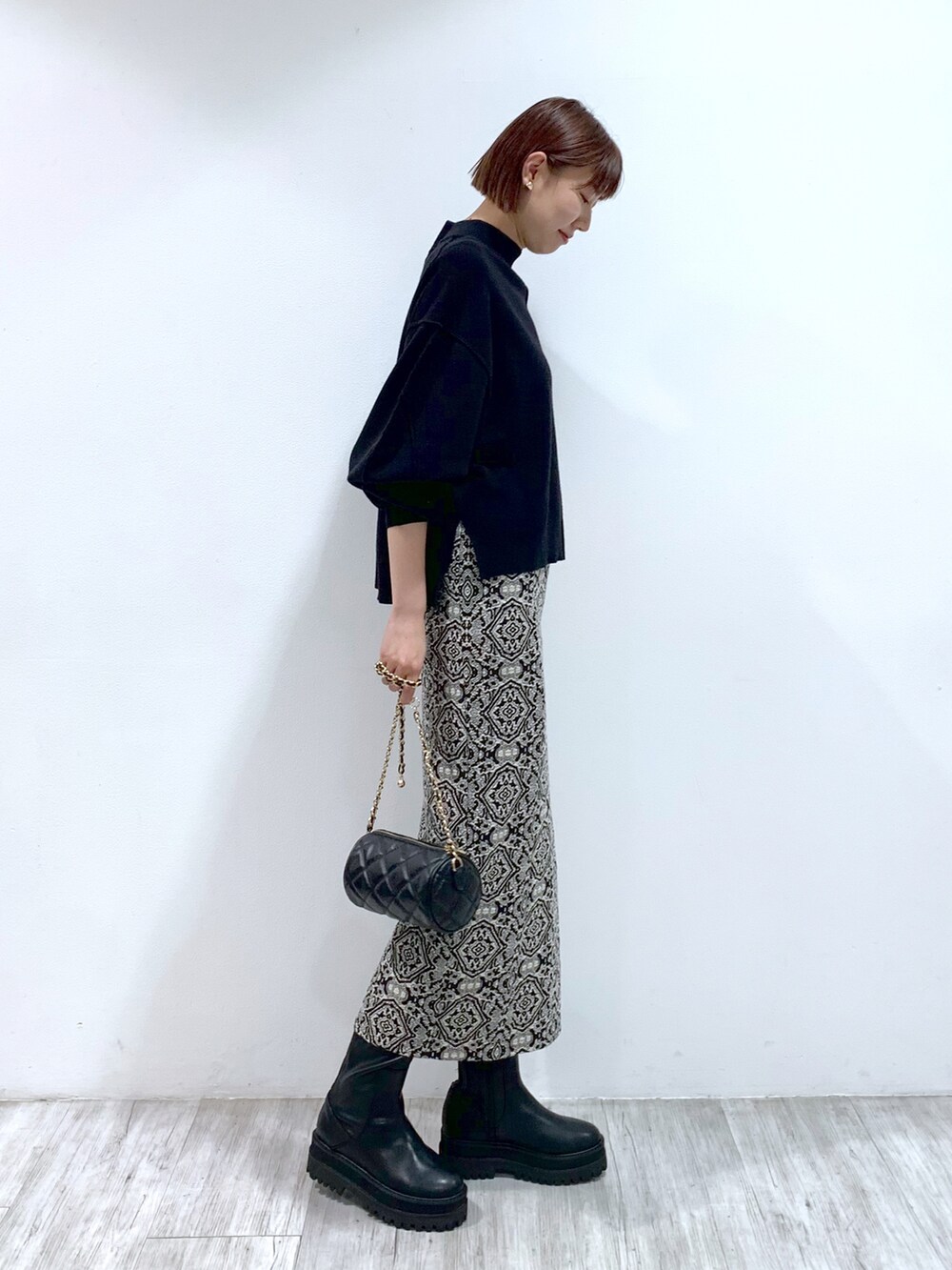 ブラック系のショルダーバッグ、ブラック系のブーツ、ブラック系のスカートを着用したレディースの秋コーディネートの3枚目の写真