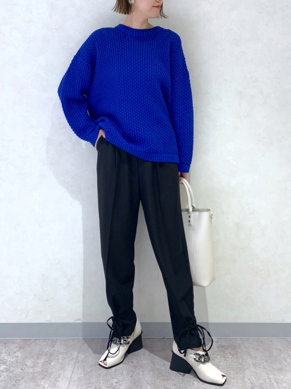 ブルー系のニット/セーター、ブラック系のその他パンツ、ホワイト系のパンプスを着用したレディースの冬コーディネートの2枚目の写真