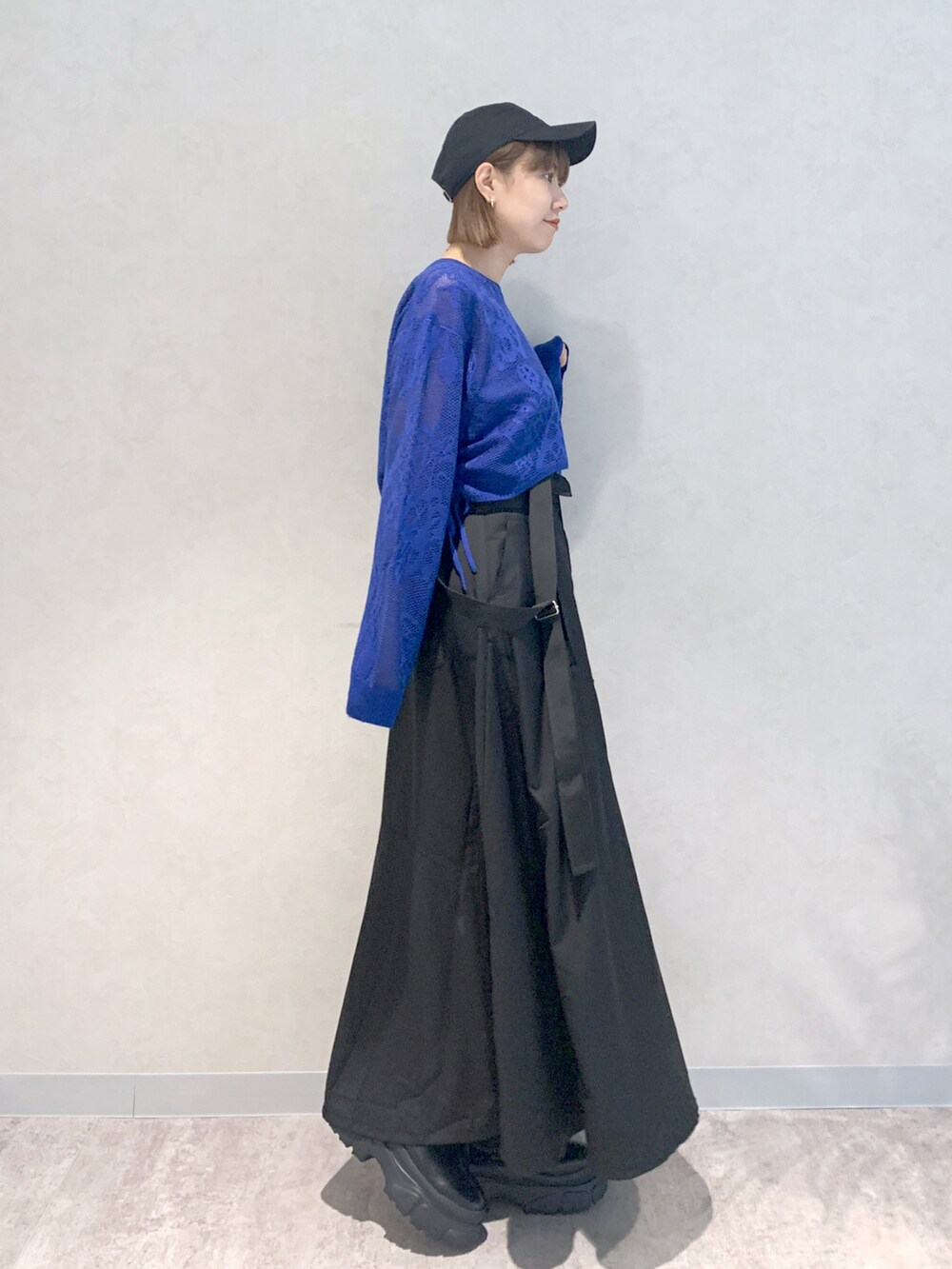 ブラック系のジャンパースカート、ブルー系のニット/セーター、ブラック系のブーツを着用したレディースの秋コーディネートの4枚目の写真