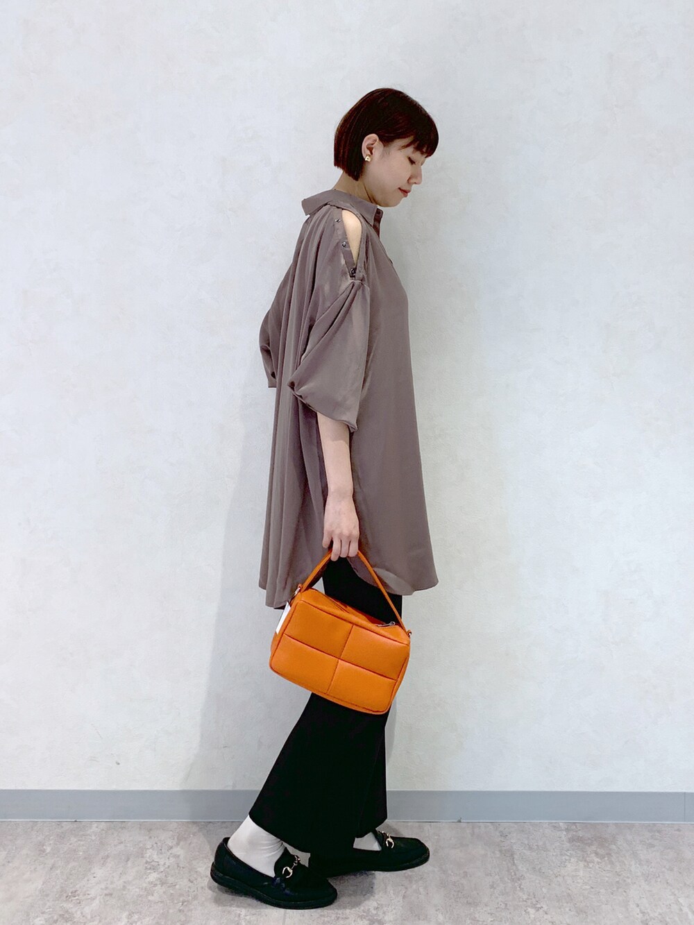 オレンジ系のショルダーバッグ、ブラック系のローファー、ブラック系のスラックスを着用したレディースの夏コーディネートの2枚目の写真