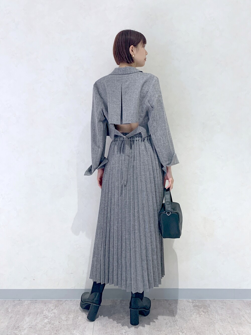 グレー系のスカート、ブラック系のショルダーバッグ、ブラック系のブーツを着用したレディースの夏コーディネートの4枚目の写真