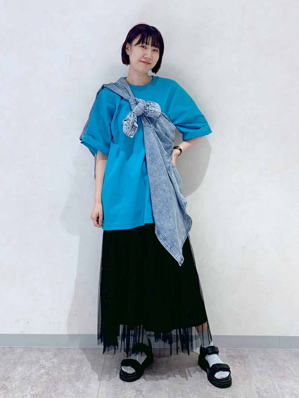 ブラック系のサンダル、ブラック系のスカート、ブルー系のシャツ/ブラウスを着用したレディースの春コーディネートの2枚目の写真