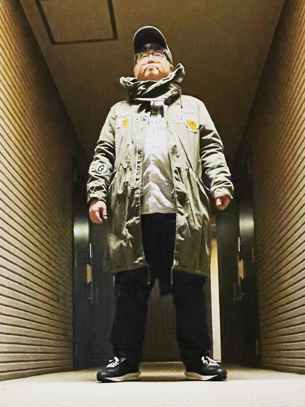 グリーン系のモッズコート、ブルー系のデニムパンツ、ブラック系のスニーカーを着用したメンズの冬コーディネートの4枚目の写真