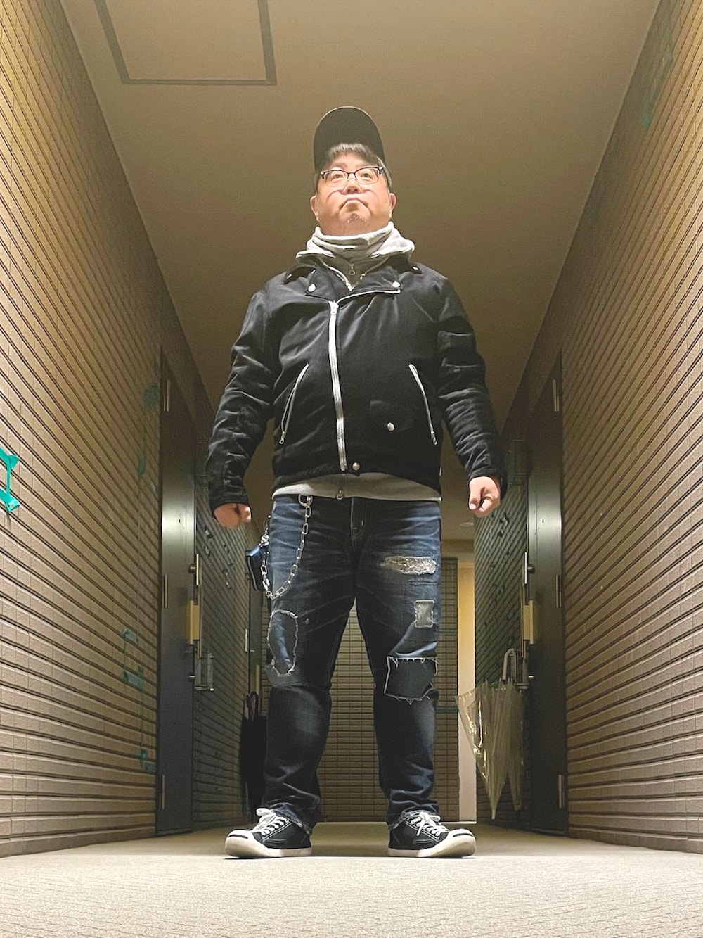 グレー系のパーカー、ブラック系のライダースジャケット、ブルー系のデニムパンツを着用したメンズの冬コーディネートの5枚目の写真