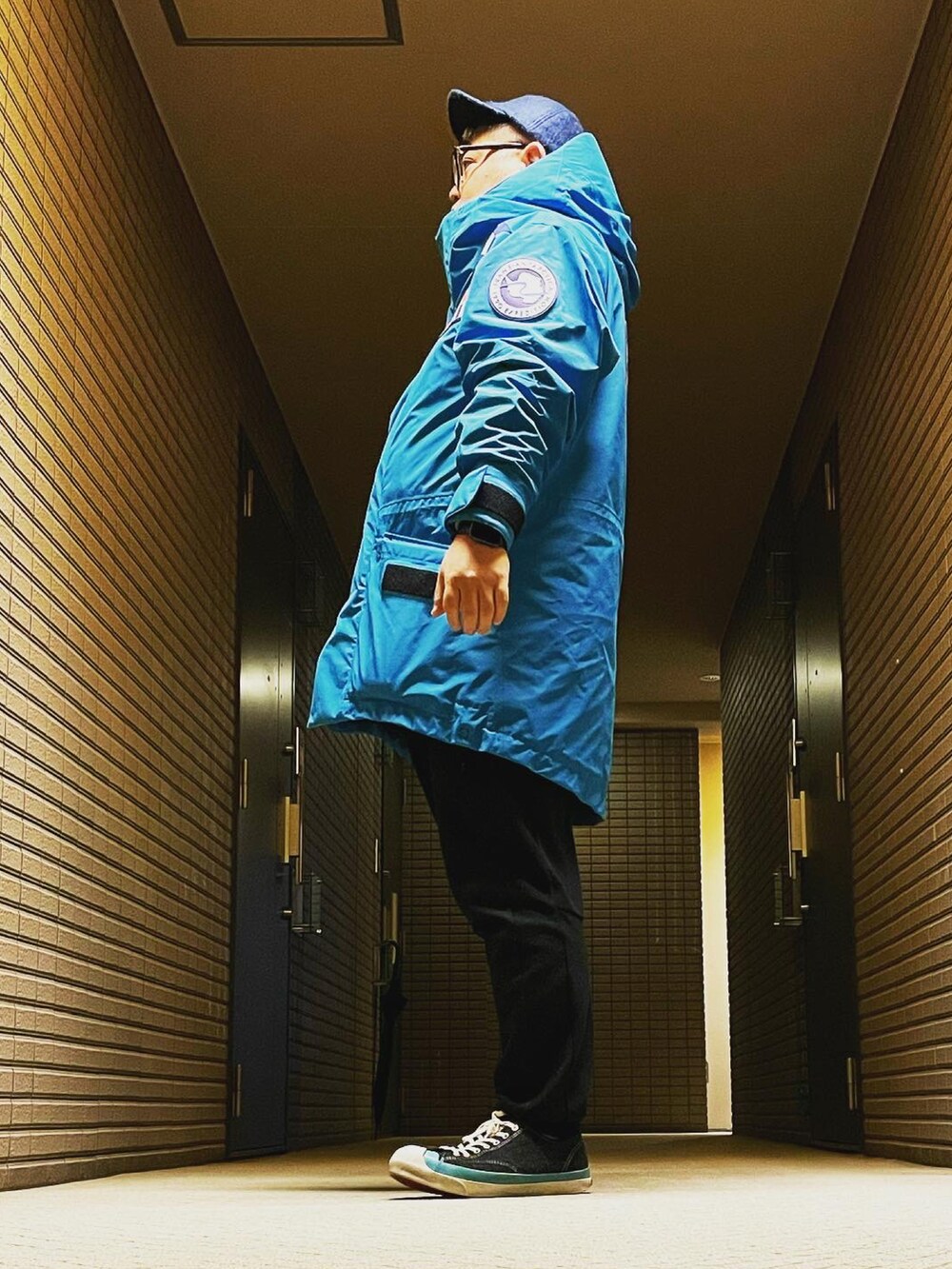 ブルー系のマウンテンパーカー、ブラック系のスウェットパンツ、ブラック系のスニーカーを着用したメンズの冬コーディネートの4枚目の写真