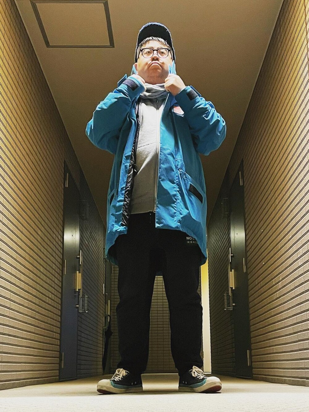 ブルー系のマウンテンパーカー、ブラック系のスウェットパンツ、ブラック系のスニーカーを着用したメンズの冬コーディネートの5枚目の写真