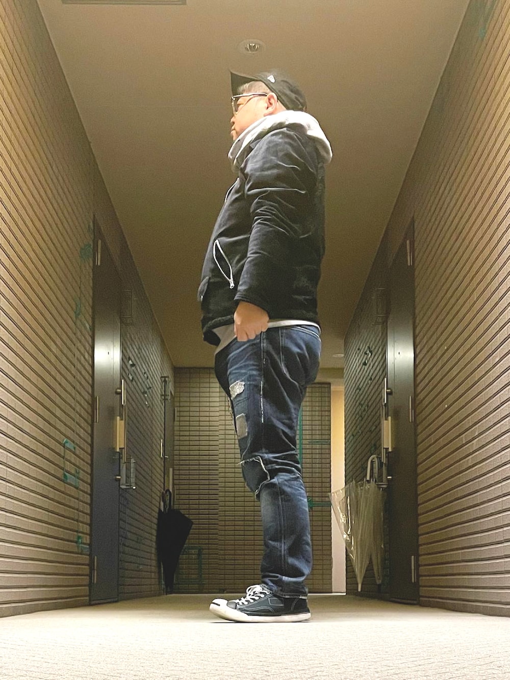 グレー系のパーカー、ブラック系のライダースジャケット、ブルー系のデニムパンツを着用したメンズの冬コーディネートの3枚目の写真