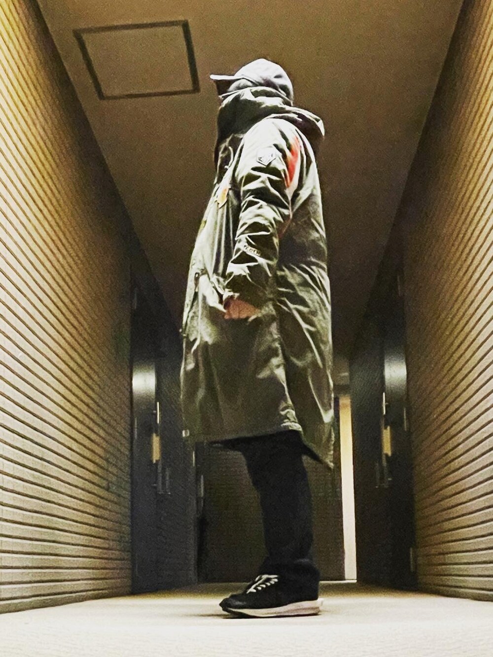 グリーン系のモッズコート、ブルー系のデニムパンツ、ブラック系のスニーカーを着用したメンズの冬コーディネートの3枚目の写真