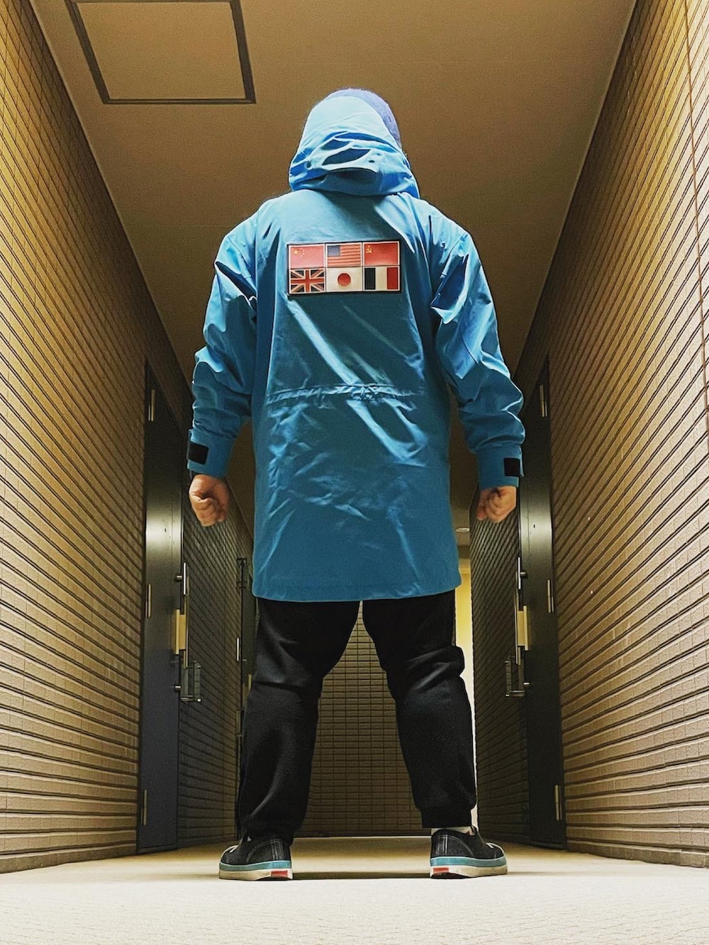 ブルー系のマウンテンパーカー、ブラック系のスウェットパンツ、ブラック系のスニーカーを着用したメンズの冬コーディネートの2枚目の写真