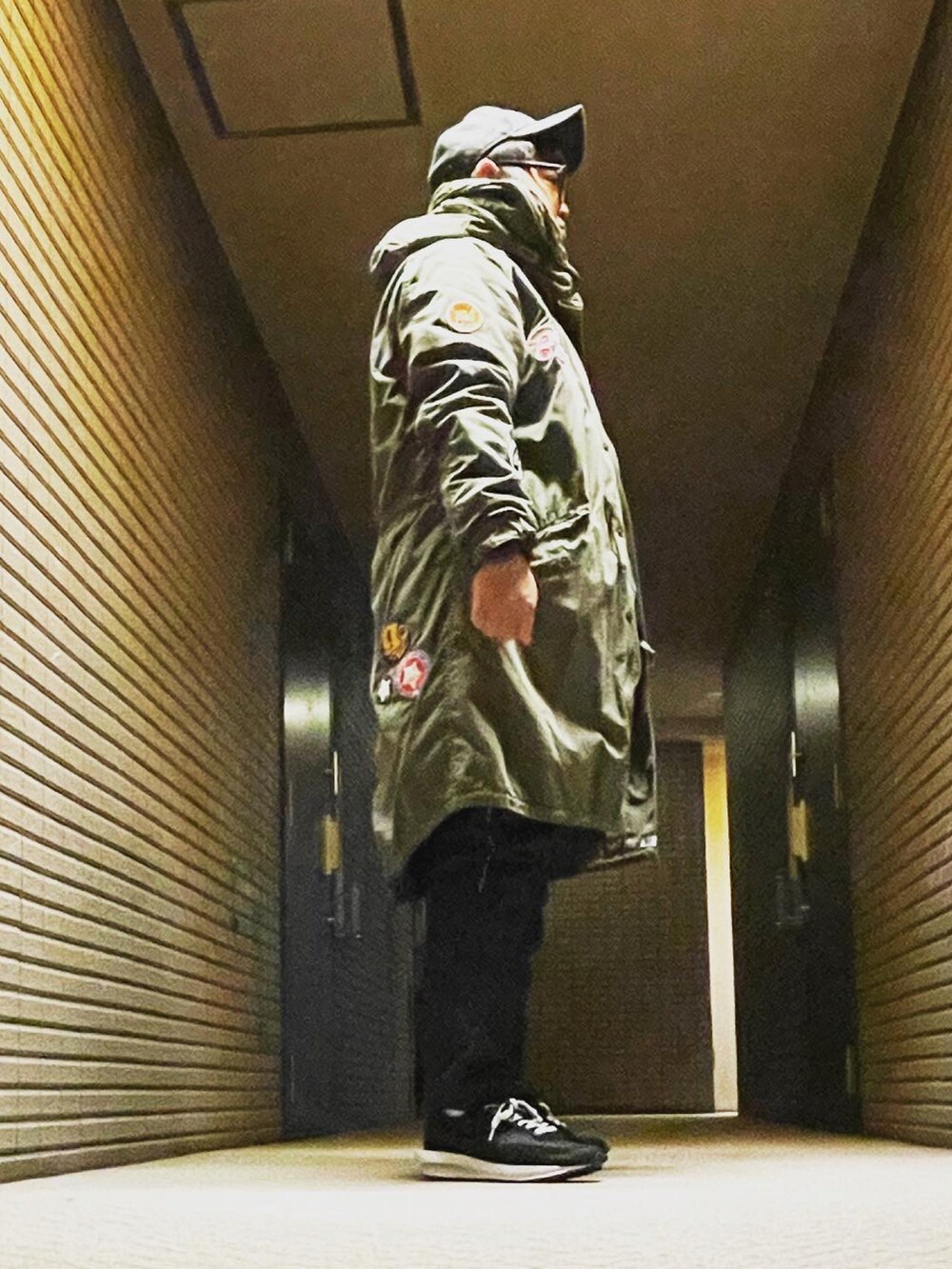 グリーン系のモッズコート、ブルー系のデニムパンツ、ブラック系のスニーカーを着用したメンズの冬コーディネートの2枚目の写真