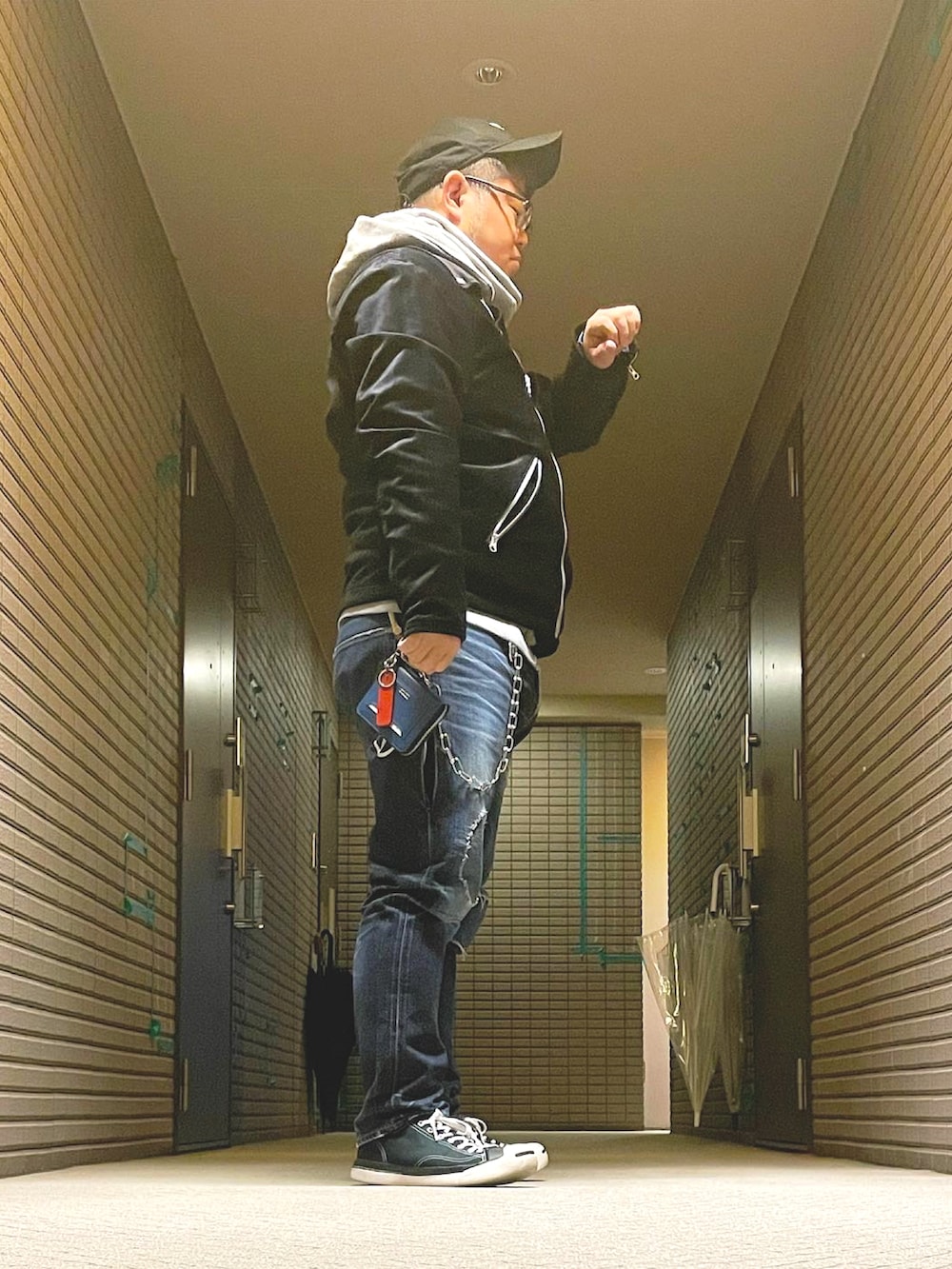 グレー系のパーカー、ブラック系のライダースジャケット、ブルー系のデニムパンツを着用したメンズの冬コーディネートの2枚目の写真