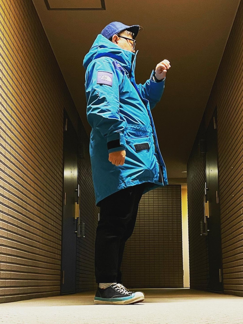 ブルー系のマウンテンパーカー、ブラック系のスウェットパンツ、ブラック系のスニーカーを着用したメンズの冬コーディネートの3枚目の写真