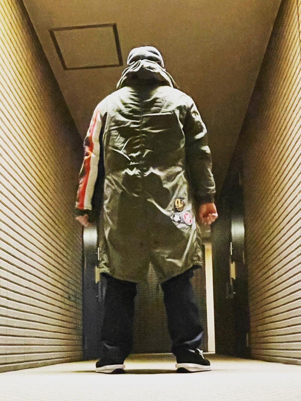 グリーン系のモッズコート、ブルー系のデニムパンツ、ブラック系のスニーカーを着用したメンズの冬コーディネートの5枚目の写真