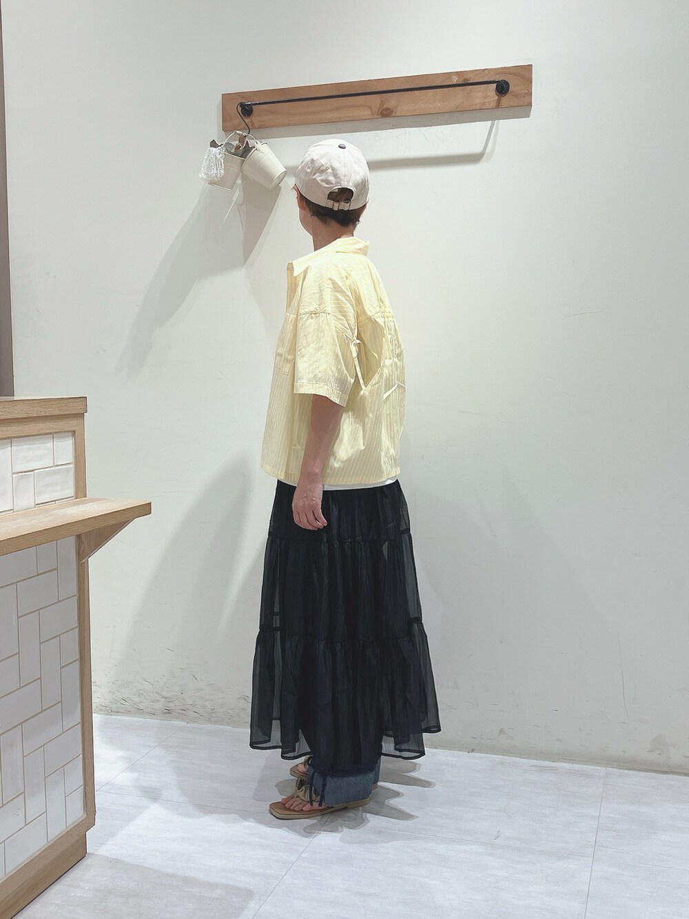 イエロー系のシャツ/ブラウス、ホワイト系のTシャツ/カットソー、ブラック系のスカートを着用したレディースの夏コーディネートの2枚目の写真