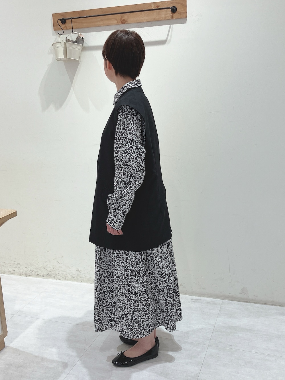 ブラック系のベスト、ブラック系のワンピース、ブラック系のハンドバッグを着用したレディースの春コーディネートの2枚目の写真