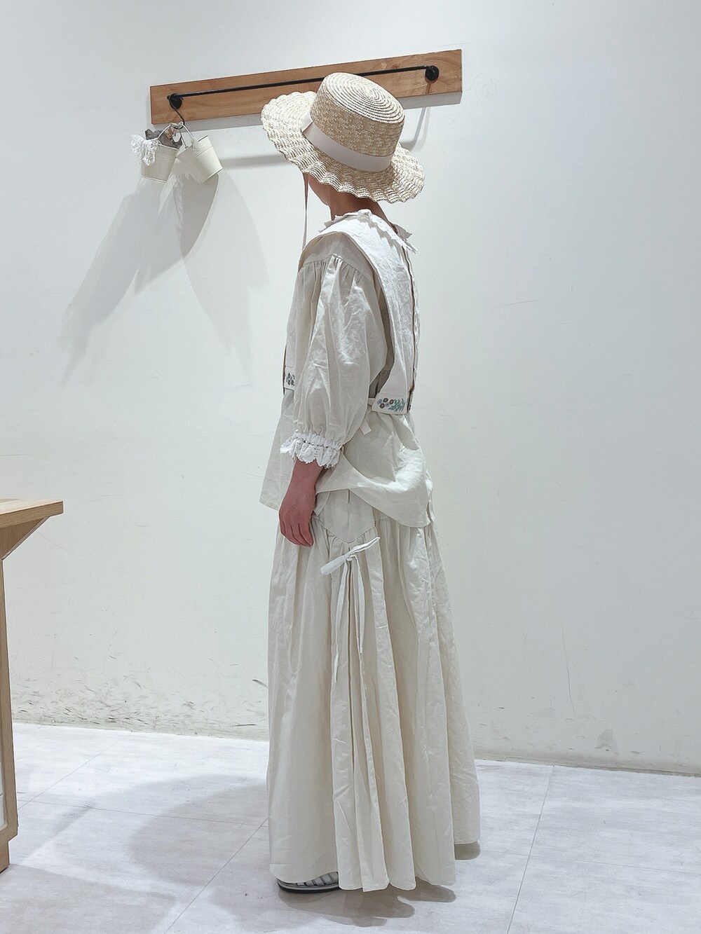 ホワイト系のベスト、ホワイト系のスカート、シルバー系のサンダルを着用したレディースの春コーディネートの2枚目の写真