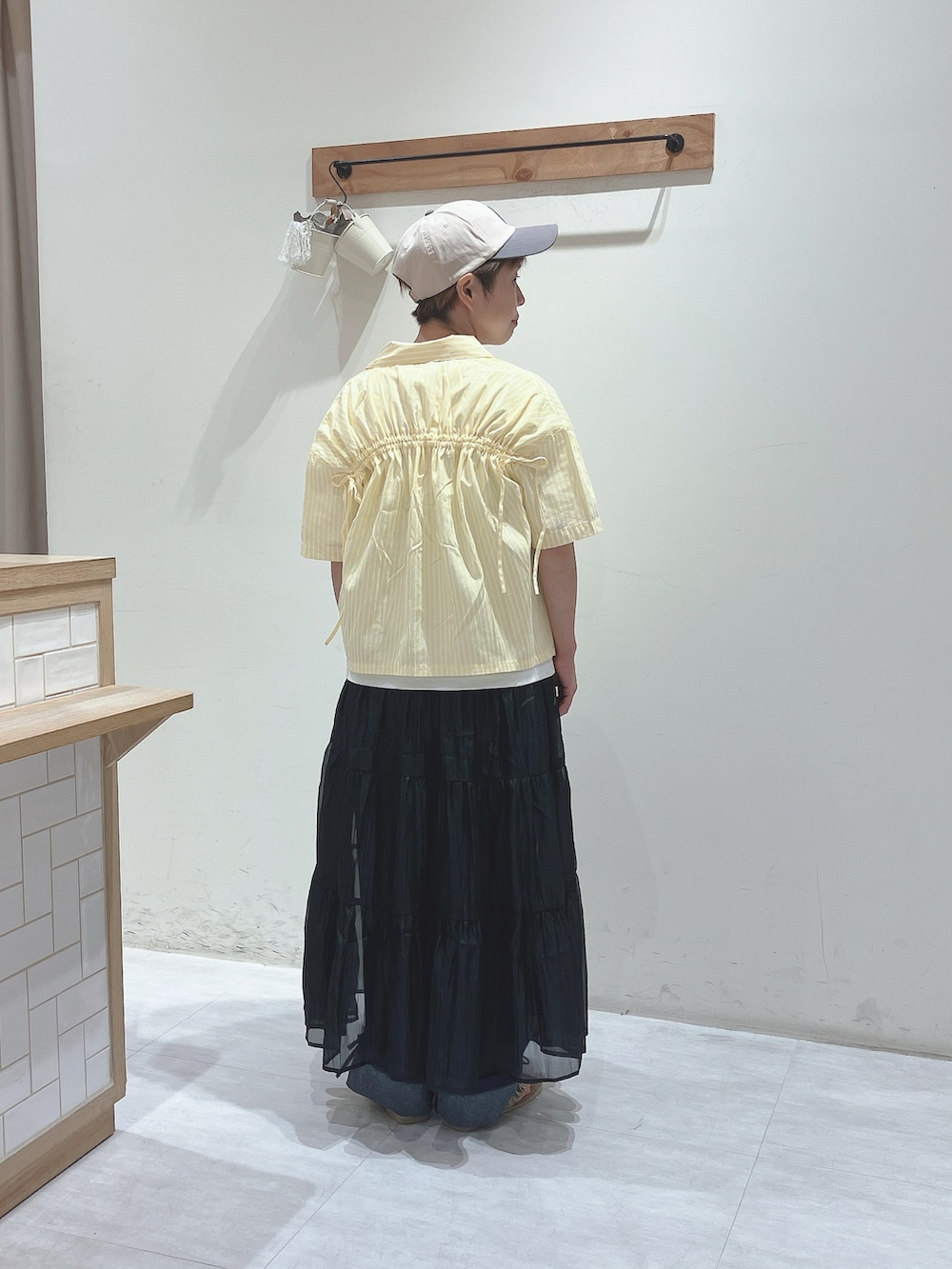 イエロー系のシャツ/ブラウス、ホワイト系のTシャツ/カットソー、ブラック系のスカートを着用したレディースの夏コーディネートの3枚目の写真