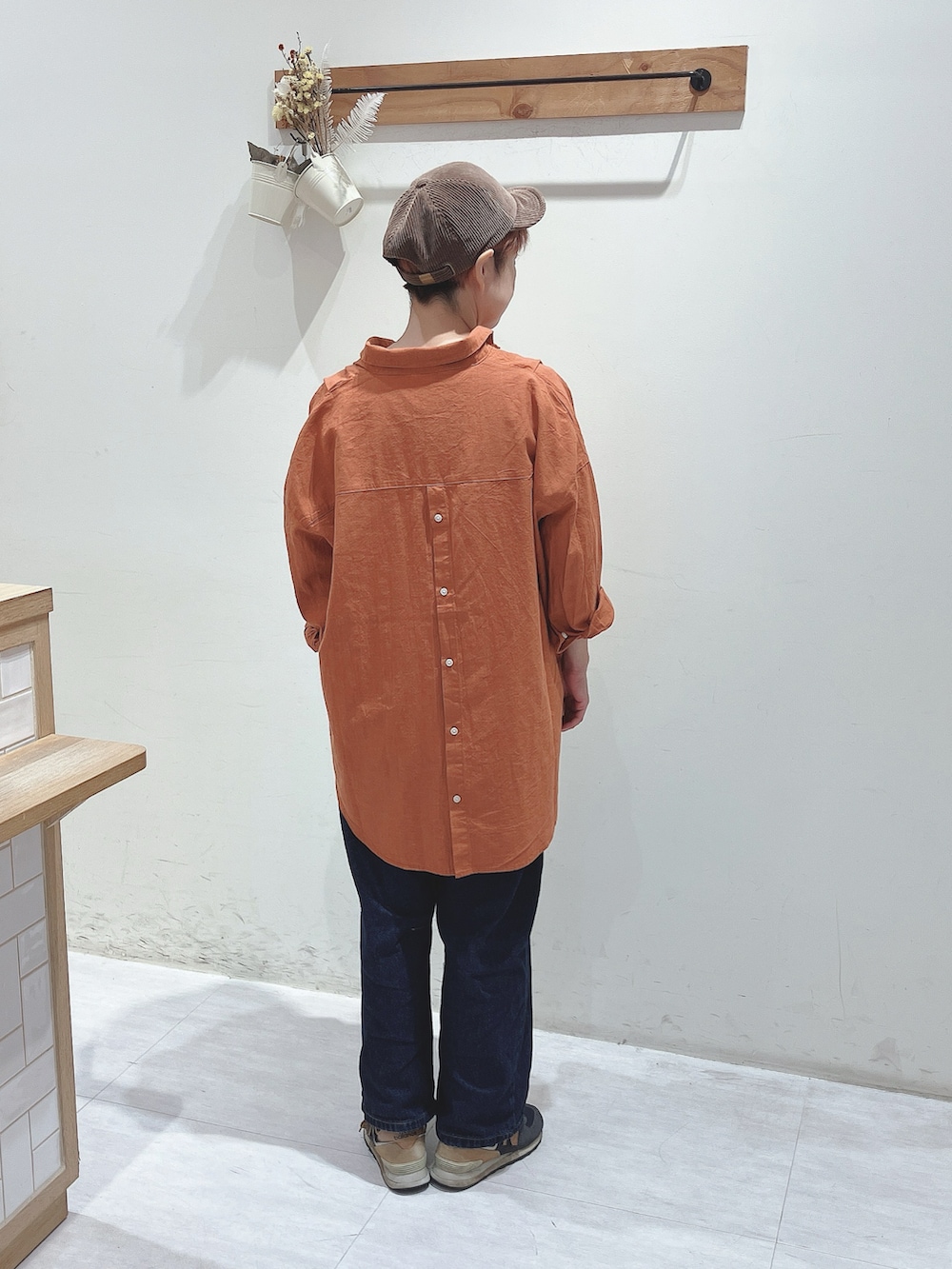 オレンジ系のシャツ/ブラウス、ブルー系のデニムパンツ、ブラウン系のキャップを着用したレディースの秋コーディネートの3枚目の写真