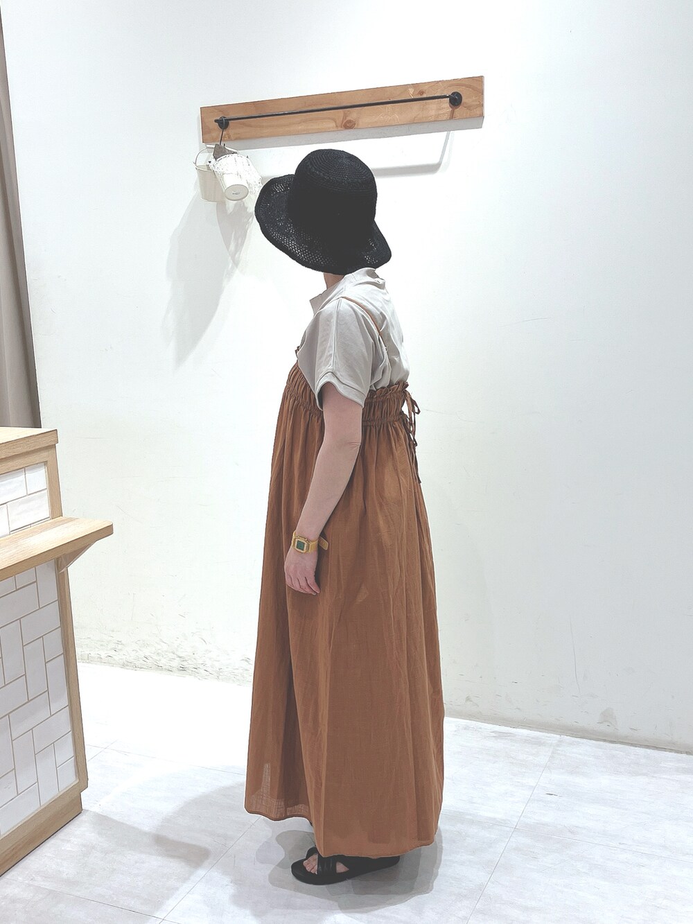 ベージュ系のTシャツ/カットソー、オレンジ系のワンピース、ブラック系のサンダルを着用したレディースの春コーディネートの2枚目の写真