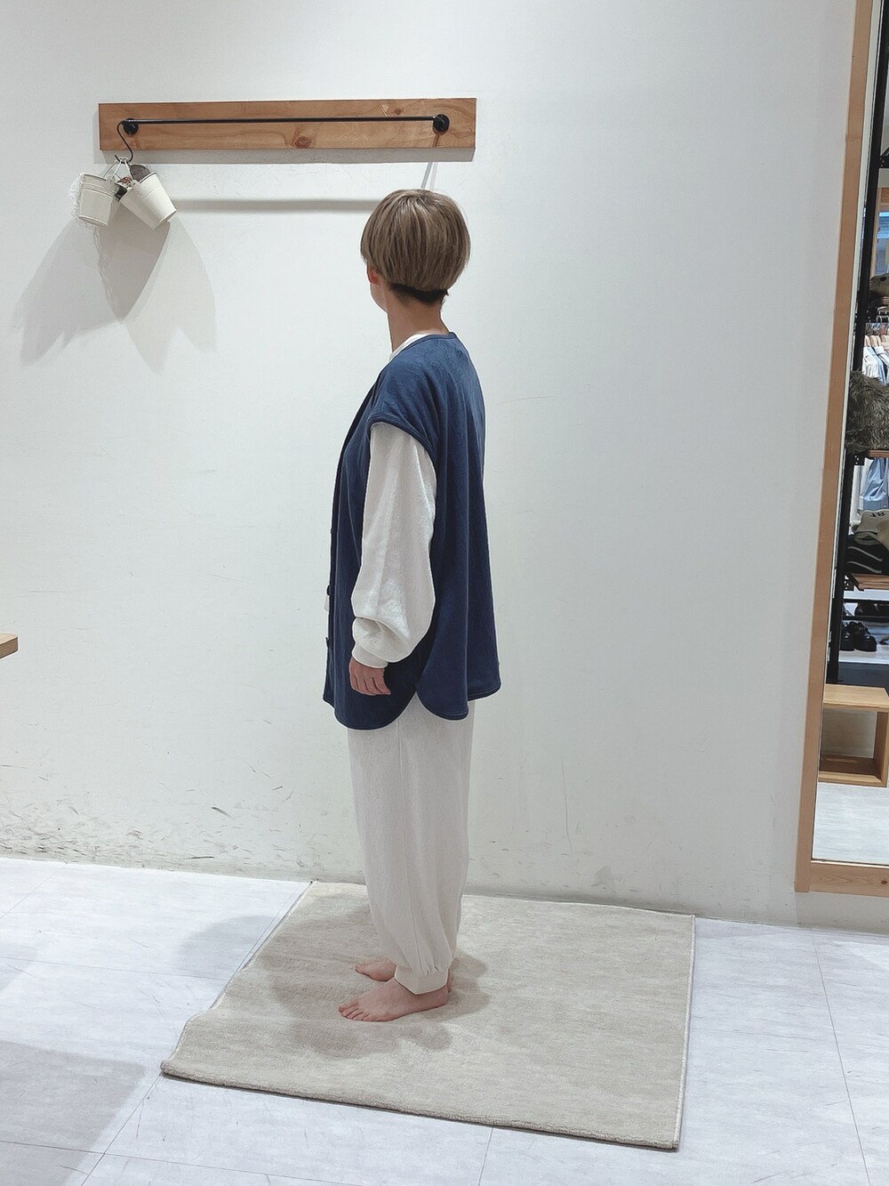 ブルー系のベスト、ホワイト系のトップス、ホワイト系のパンツを着用したレディースの秋コーディネートの2枚目の写真