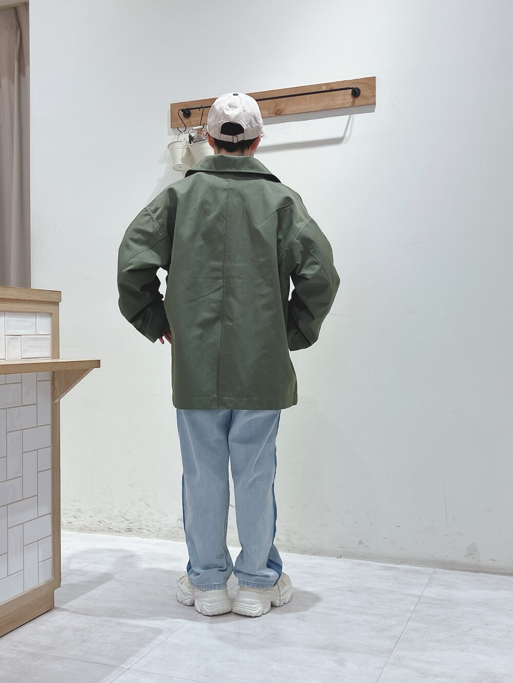 グリーン系のその他アウター、グリーン系のTシャツ/カットソー、ブルー系のデニムパンツを着用したレディースの冬コーディネートの2枚目の写真