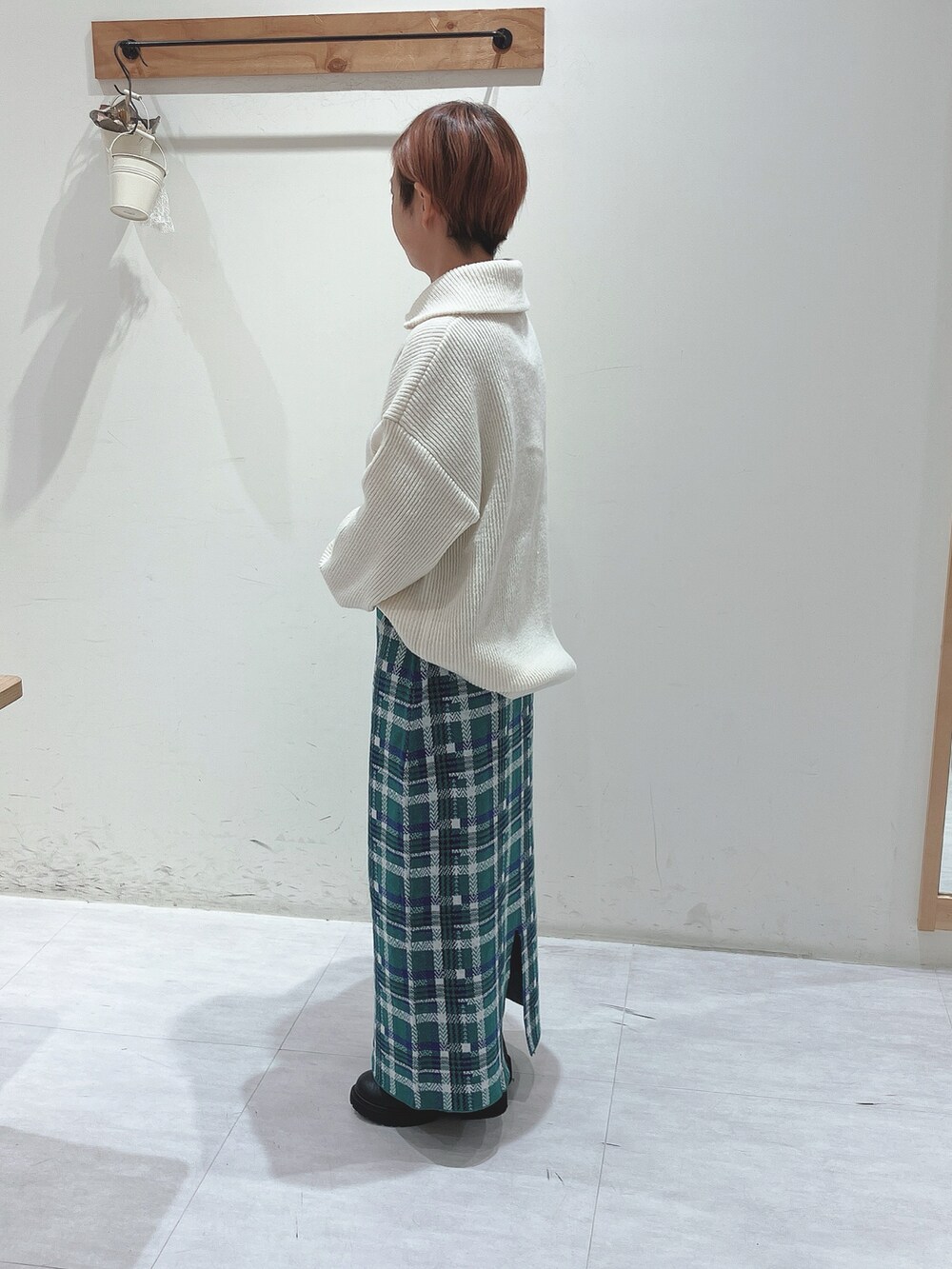 ホワイト系のニット/セーター、グリーン系のスカート、ブラック系のブーツを着用したレディースの秋コーディネートの2枚目の写真