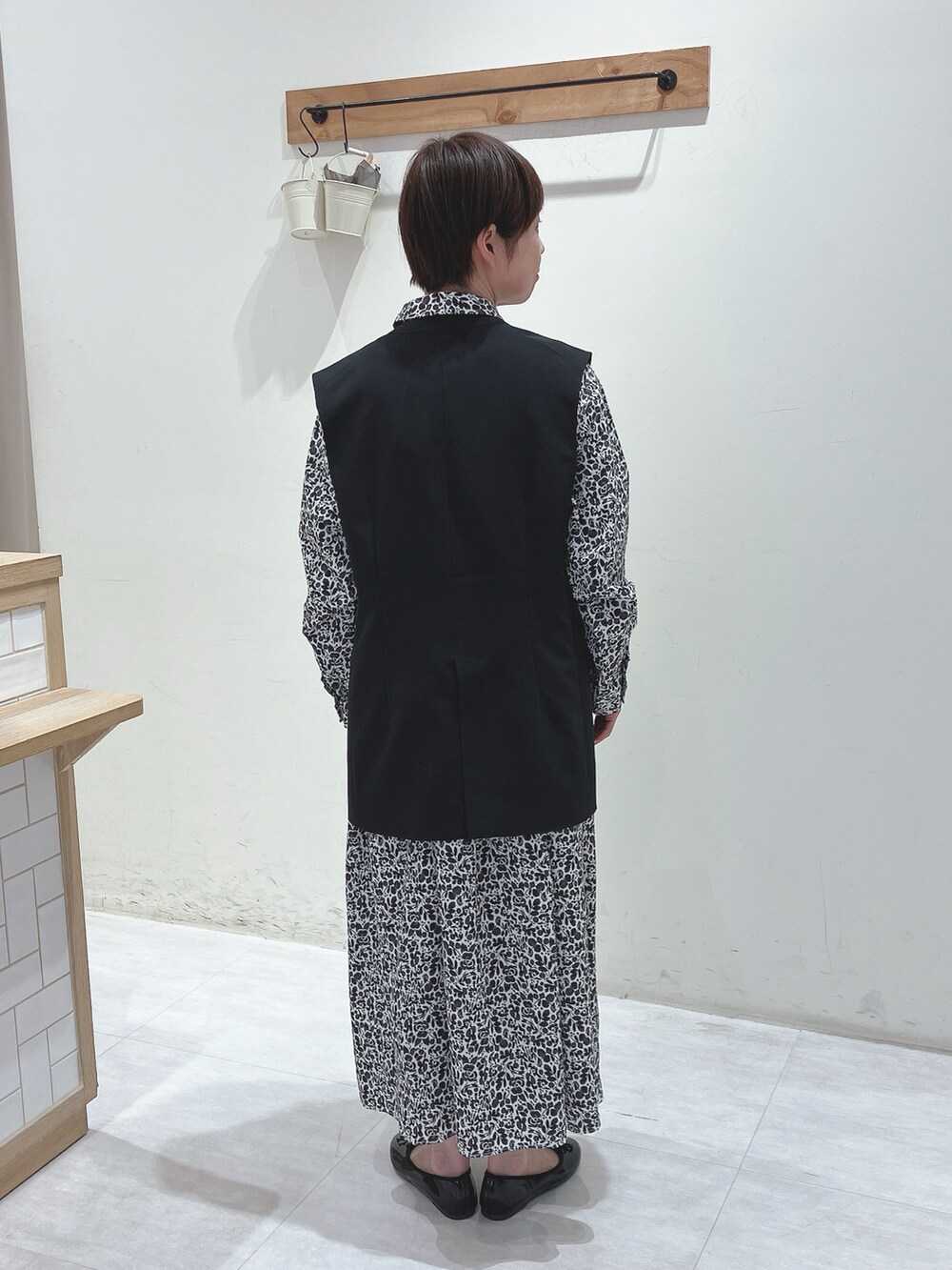 ブラック系のベスト、ブラック系のワンピース、ブラック系のハンドバッグを着用したレディースの春コーディネートの3枚目の写真