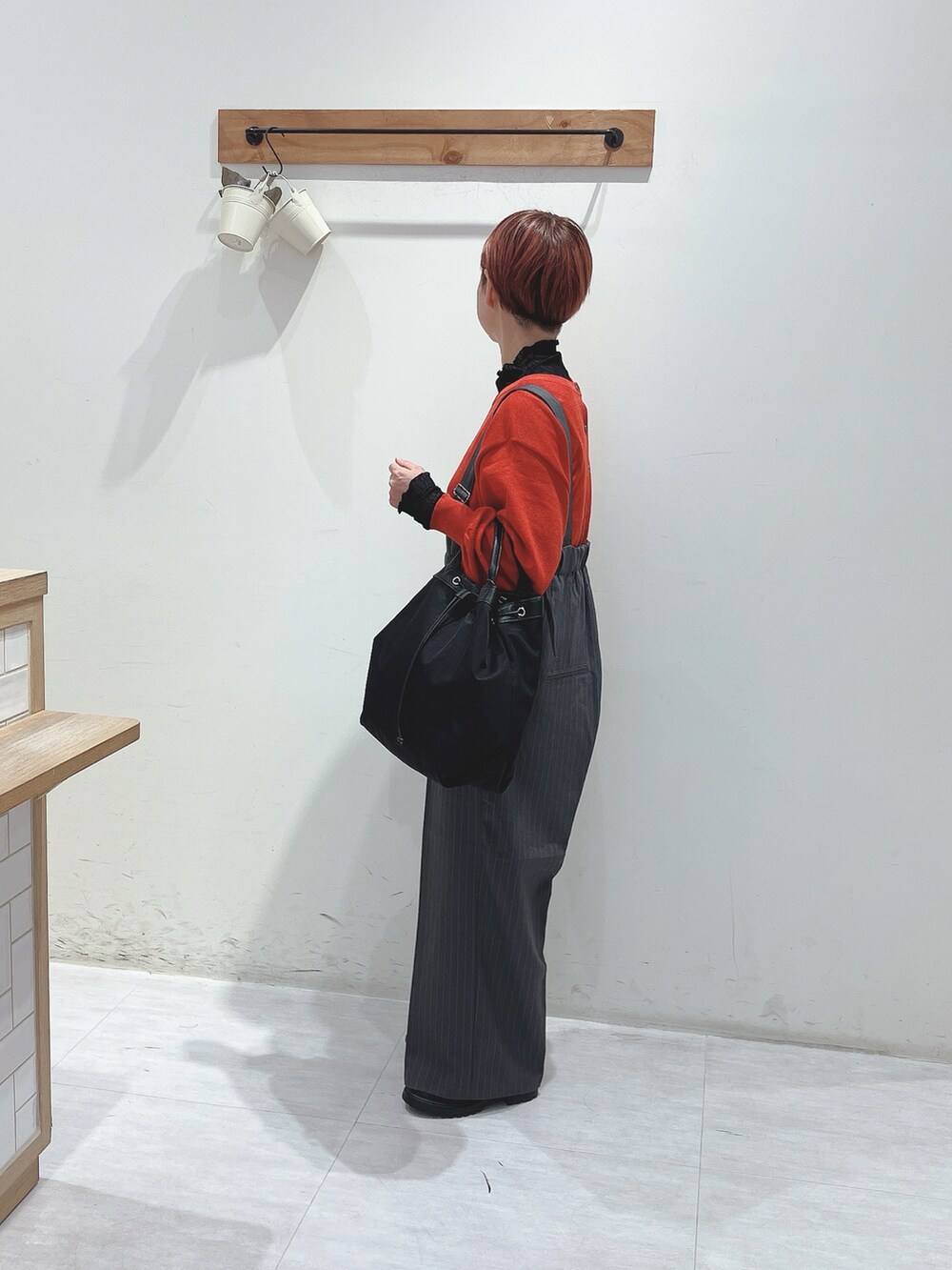 グレー系のその他パンツ、レッド系のカーディガン/ボレロ、ブラック系のバッグを着用したレディースの秋コーディネートの2枚目の写真