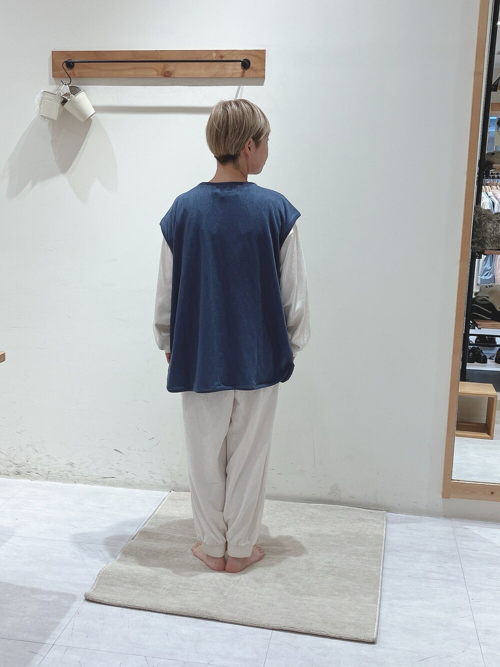 ブルー系のベスト、ホワイト系のトップス、ホワイト系のパンツを着用したレディースの秋コーディネートの3枚目の写真