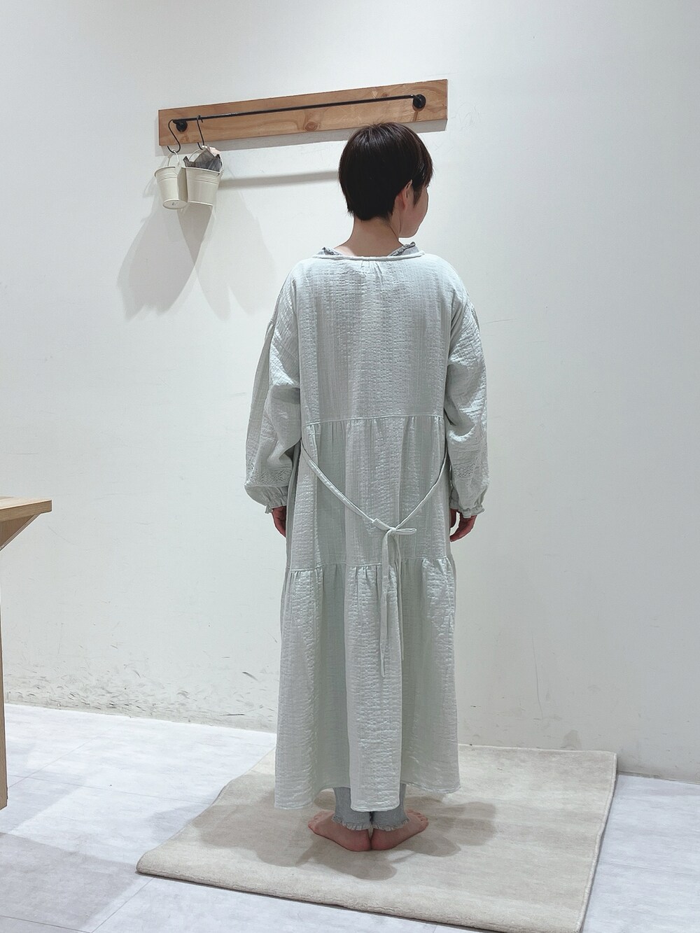 グリーン系のワンピース、グレー系のTシャツ/カットソー、グレー系のパンツを着用したレディースの冬コーディネートの3枚目の写真