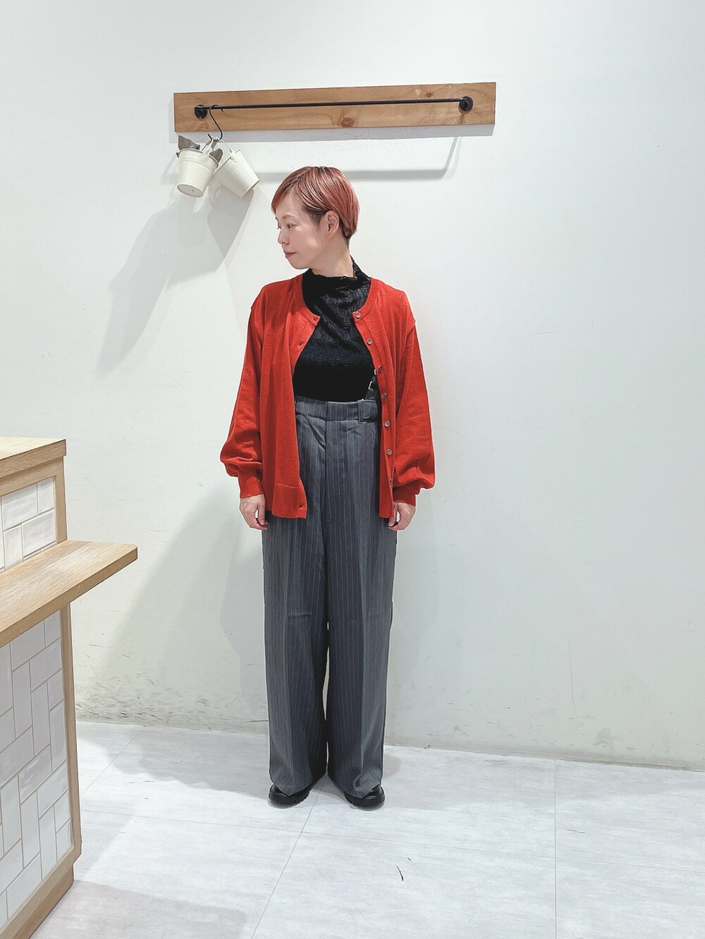 グレー系のその他パンツ、レッド系のカーディガン/ボレロ、ブラック系のバッグを着用したレディースの秋コーディネートの4枚目の写真