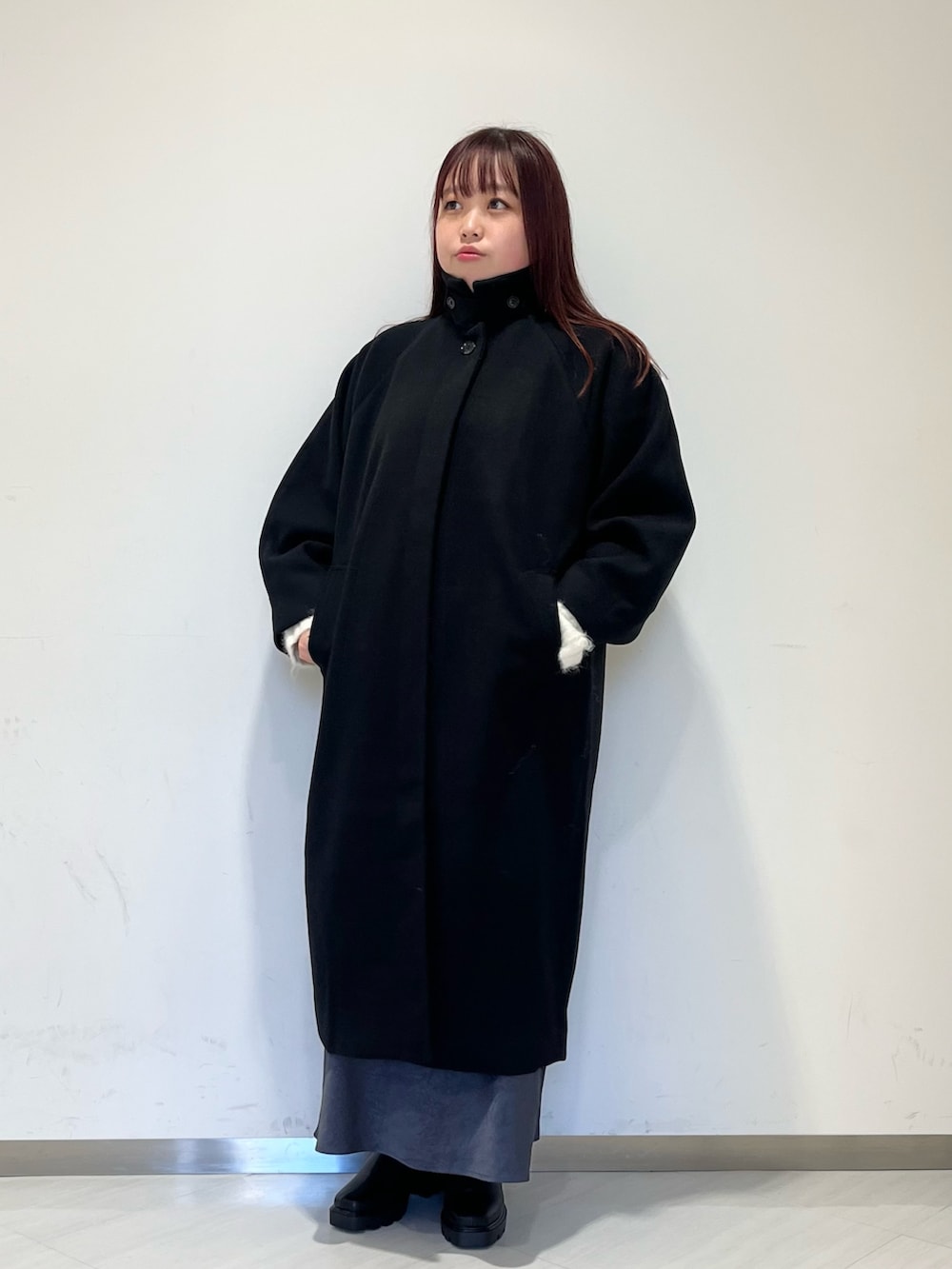 ブラック系のステンカラーコート、ホワイト系のニット/セーター、グレー系のスカートを着用したレディースの冬コーディネートの3枚目の写真