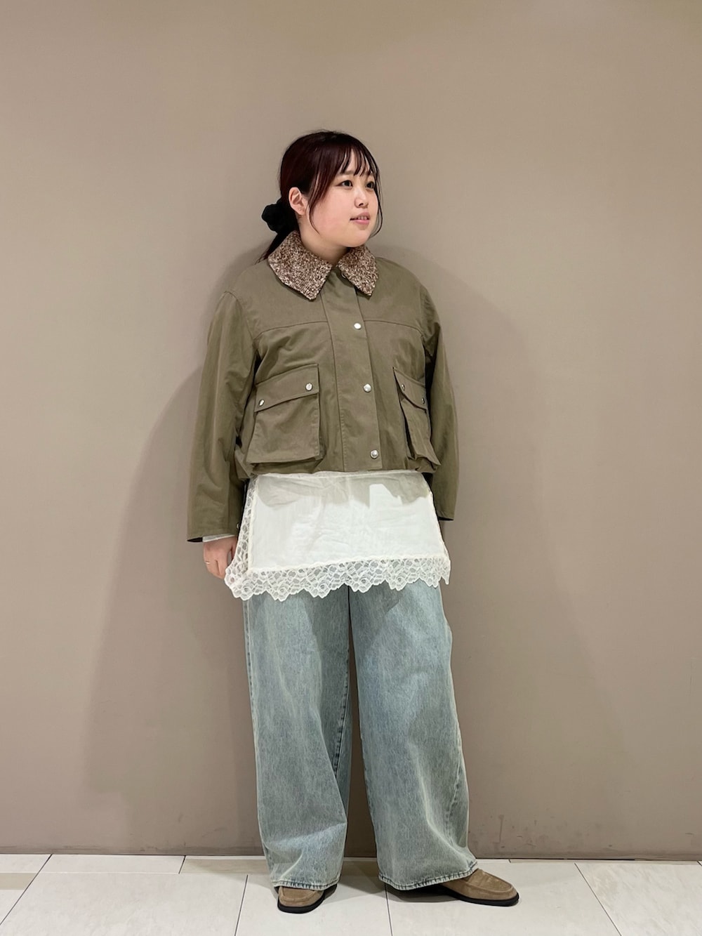 ホワイト系のキャミソール、グリーン系のブルゾン、ブルー系のデニムパンツを着用したレディースの冬コーディネートの2枚目の写真