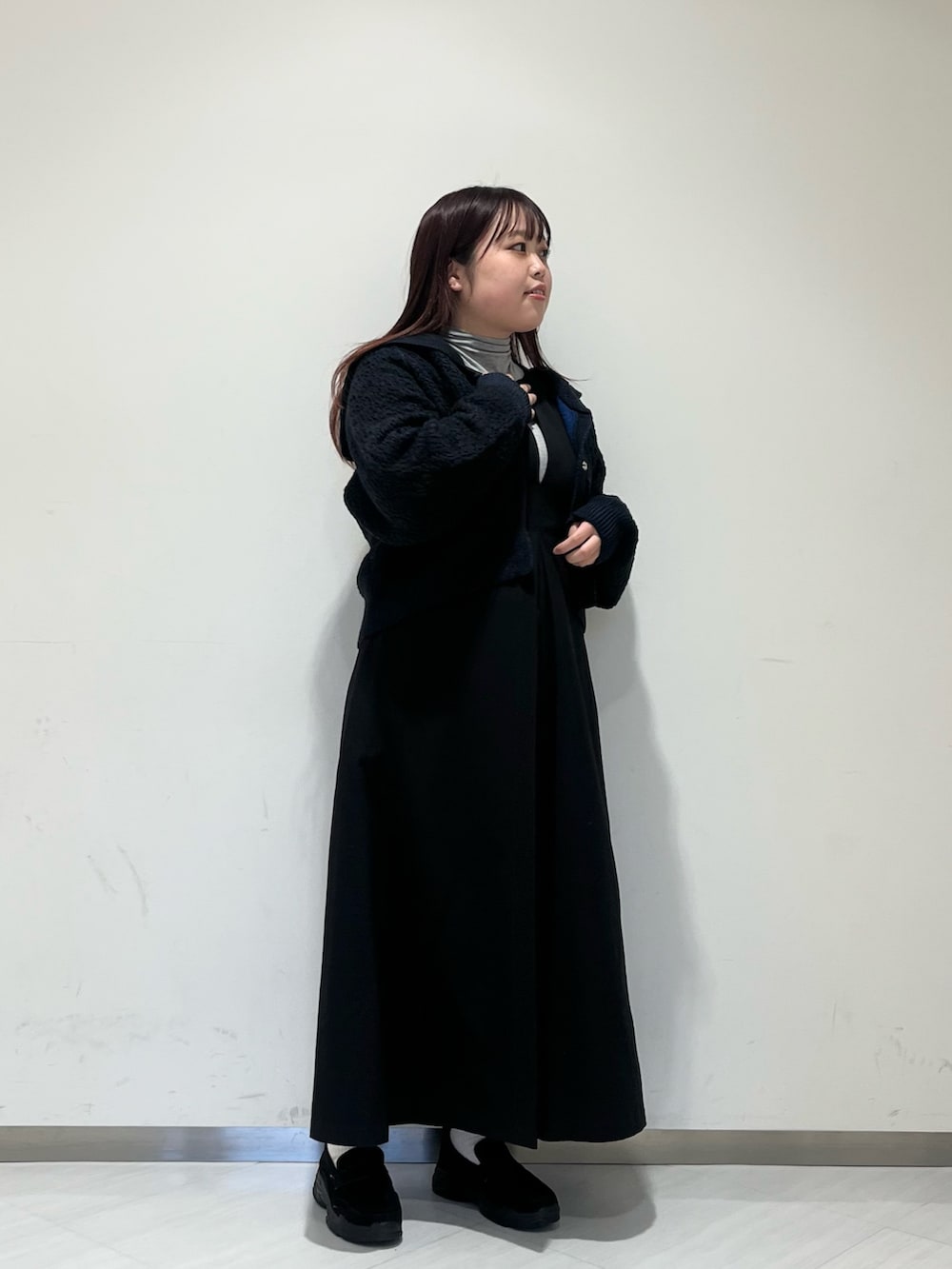 グレー系のステンカラーコート、グレー系のTシャツ/カットソー、ブラック系のワンピースを着用したレディースの冬コーディネートの2枚目の写真