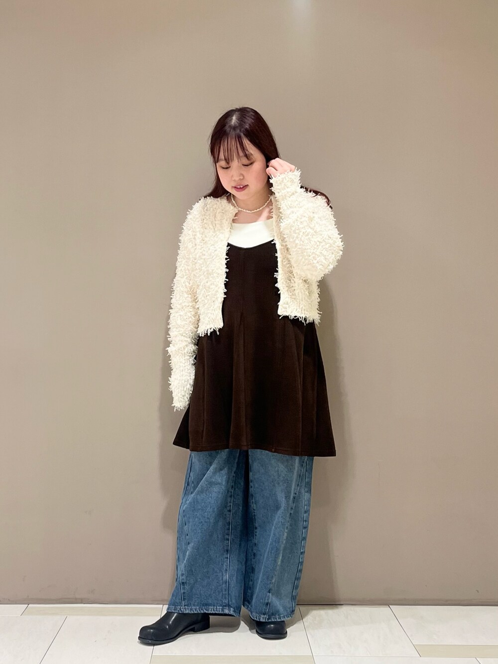 ブラウン系のワンピース、ブラック系のショルダーバッグ、ホワイト系のニット/セーターを着用したレディースの秋コーディネートの2枚目の写真