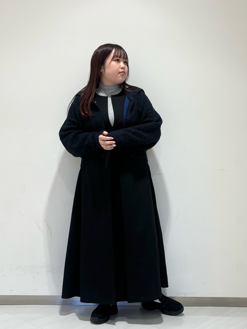 グレー系のステンカラーコート、グレー系のTシャツ/カットソー、ブラック系のワンピースを着用したレディースの冬コーディネートの4枚目の写真