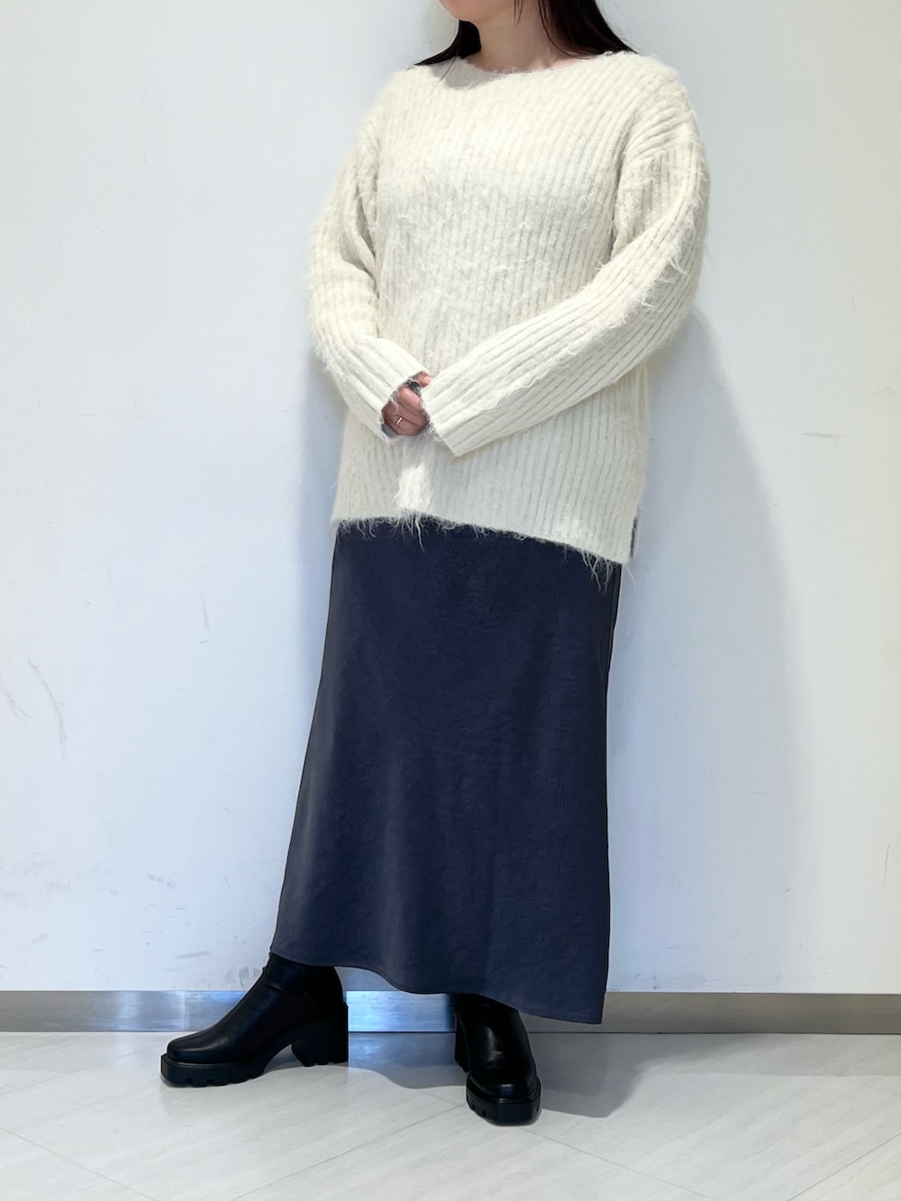 ブラック系のステンカラーコート、ホワイト系のニット/セーター、グレー系のスカートを着用したレディースの冬コーディネートの4枚目の写真