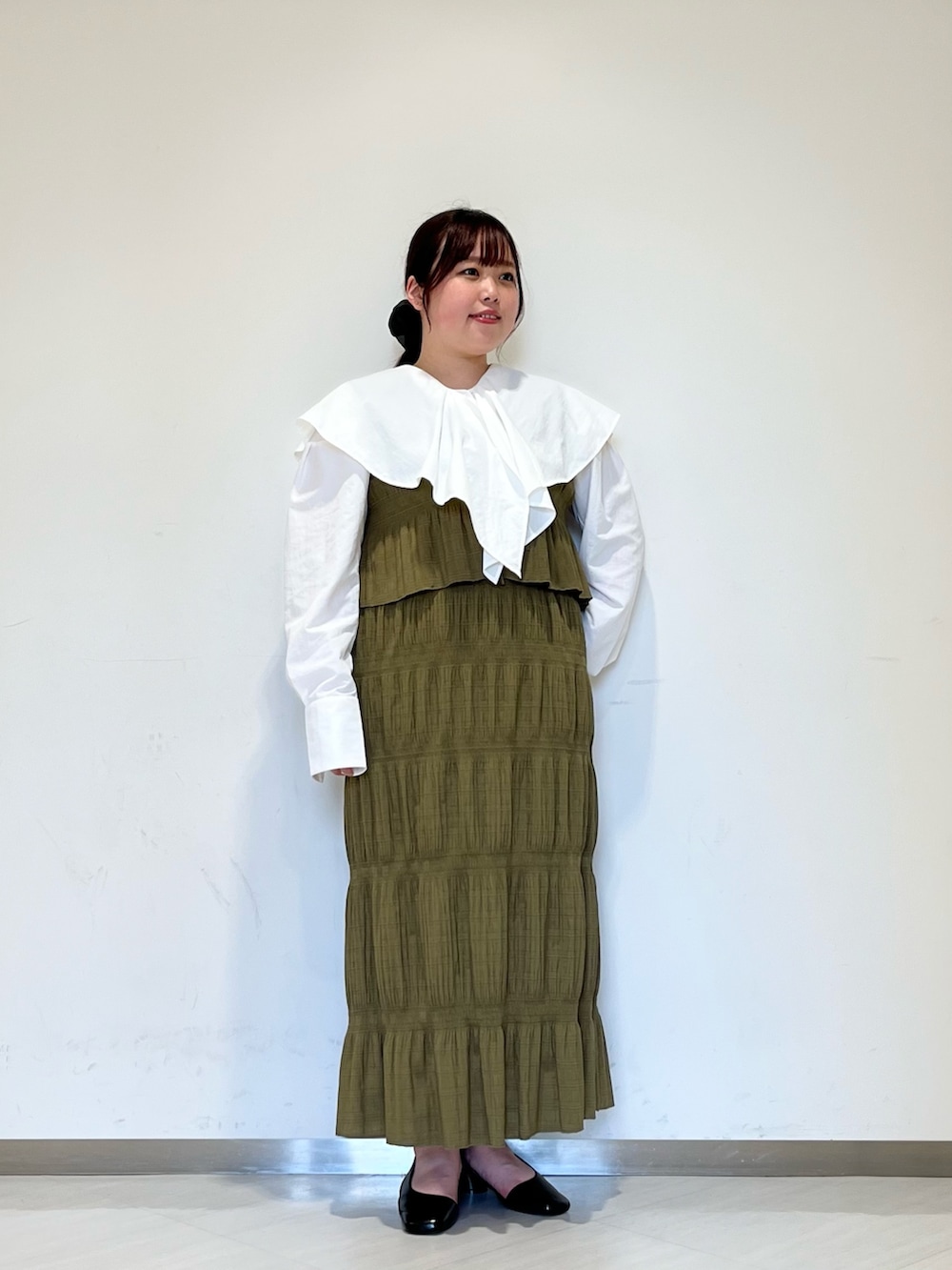 グレー系のステンカラーコート、グリーン系のセットアップ、ブラック系のパンプスを着用したレディースの冬コーディネートの5枚目の写真