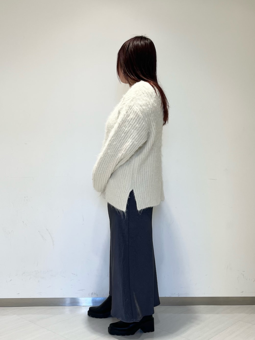 ブラック系のステンカラーコート、ホワイト系のニット/セーター、グレー系のスカートを着用したレディースの冬コーディネートの5枚目の写真