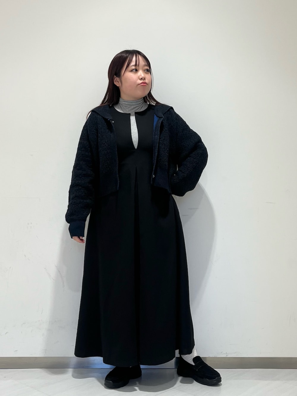 グレー系のステンカラーコート、グレー系のTシャツ/カットソー、ブラック系のワンピースを着用したレディースの冬コーディネートの3枚目の写真