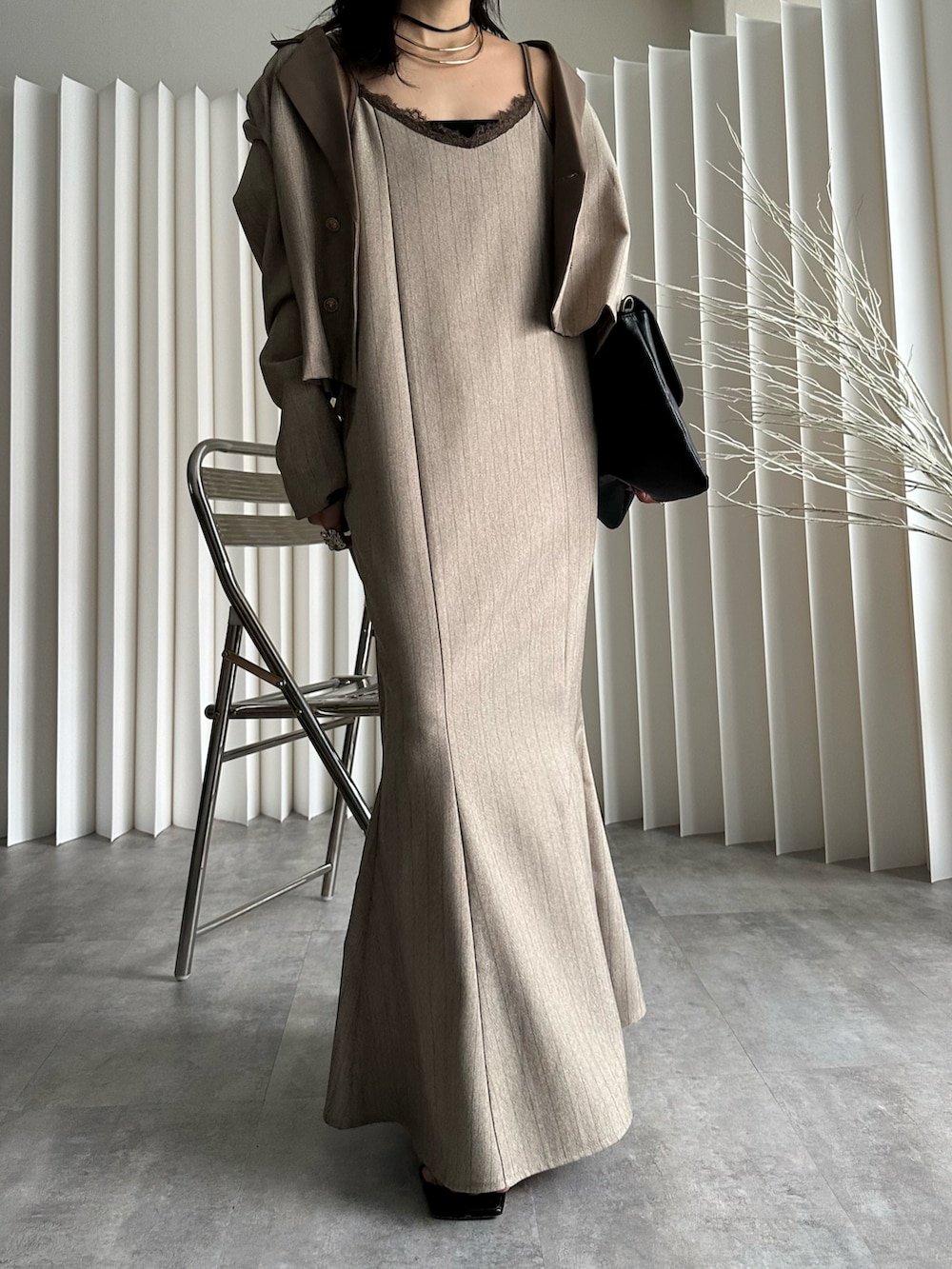 ブラック系のショルダーバッグ、ベージュ系のテーラードジャケット、ベージュ系のワンピースを着用したレディースの冬コーディネートの3枚目の写真