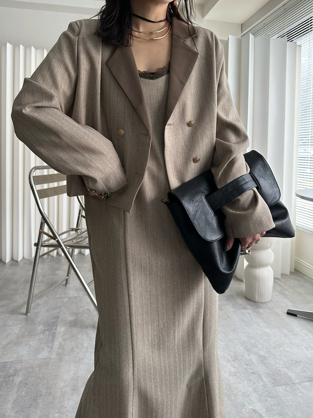 ブラック系のショルダーバッグ、ベージュ系のテーラードジャケット、ベージュ系のワンピースを着用したレディースの冬コーディネートの2枚目の写真