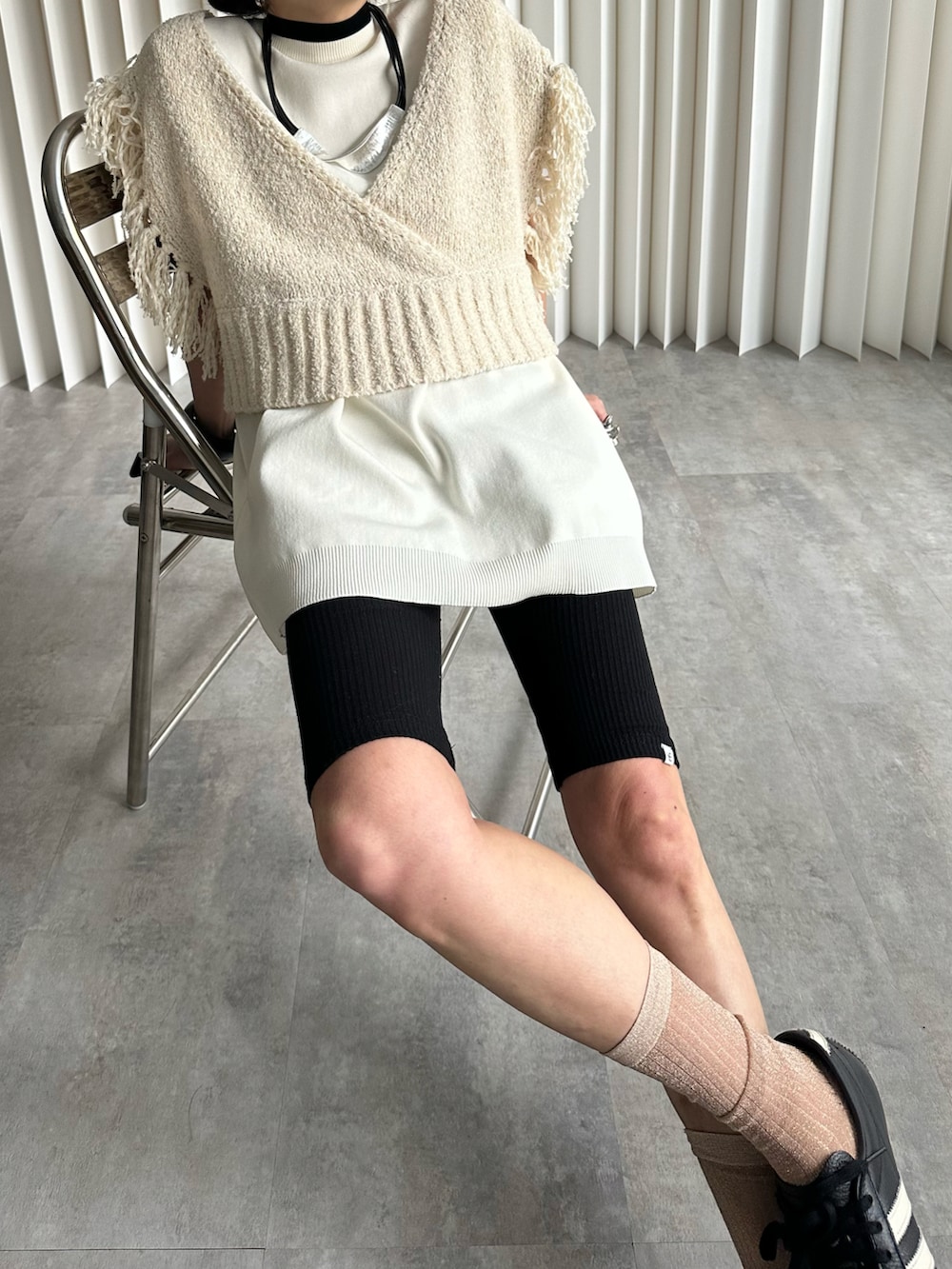 ベージュ系のベスト、ブラック系のスニーカー、ブラック系のレギンス/スパッツを着用したレディースの冬コーディネートの2枚目の写真