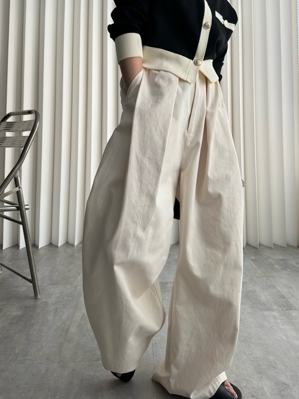 ブラック系のショルダーバッグ、ブラック系のカーディガン/ボレロ、ホワイト系のチノパンツを着用したレディースの冬コーディネートの3枚目の写真