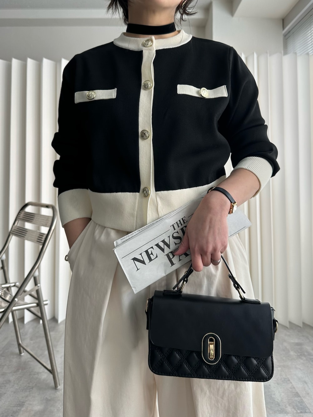 ブラック系のショルダーバッグ、ブラック系のカーディガン/ボレロ、ホワイト系のチノパンツを着用したレディースの冬コーディネートの2枚目の写真