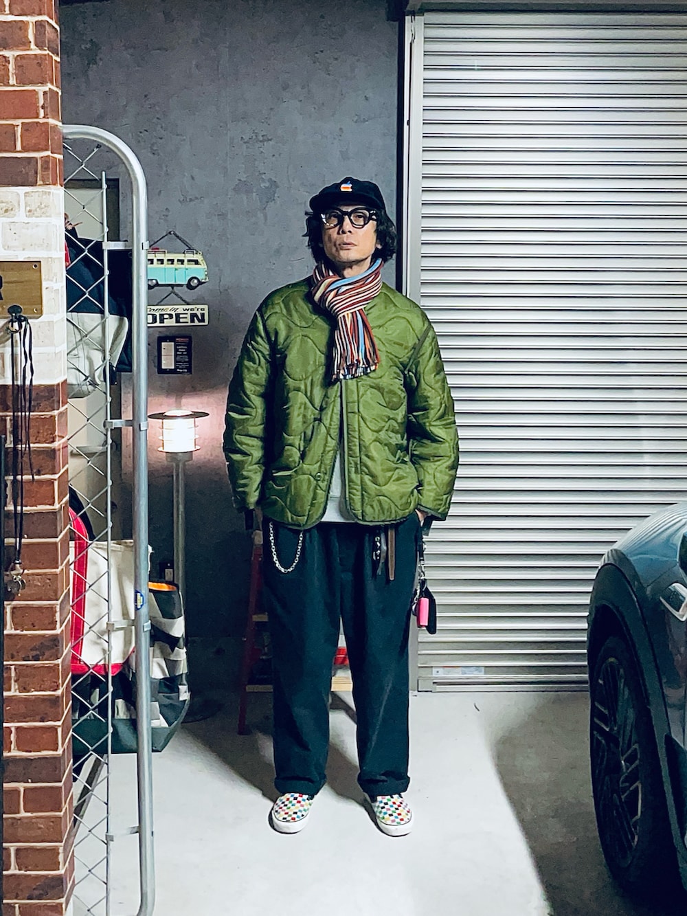 グリーン系のミリタリージャケット、ブラック系のチノパンツ、ブラック系のサングラスを着用したメンズの冬コーディネートの2枚目の写真